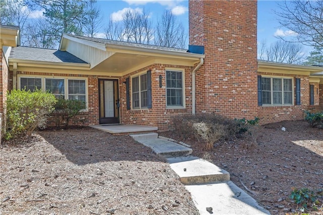 entrance to property with a chimney and brick siding