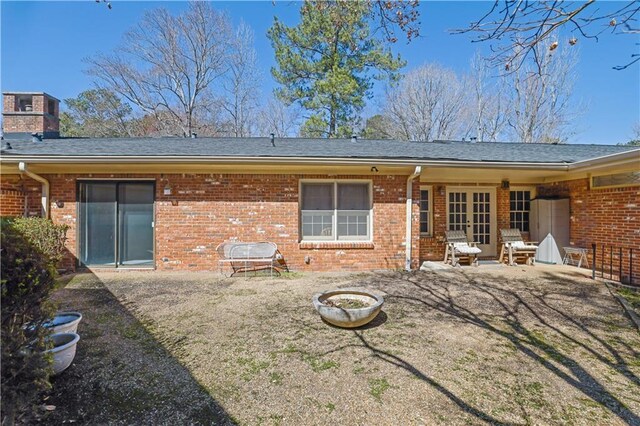 rear view of property with french doors, brick siding, roof with shingles, a chimney, and a patio area