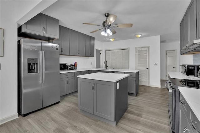 kitchen with appliances with stainless steel finishes, gray cabinets, light countertops, and a kitchen island