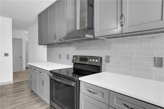 kitchen with gray cabinets, wall chimney range hood, and stainless steel electric range