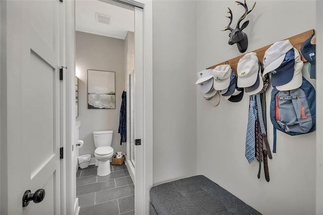 bathroom featuring a stall shower, toilet, and tile patterned flooring