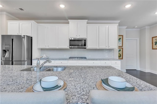 6179 Ashbranch Dr, Acworth, GA 30101 - kitchen with stainless steel appliances, a sink, light stone counters, ornamental molding, and white cabinetry