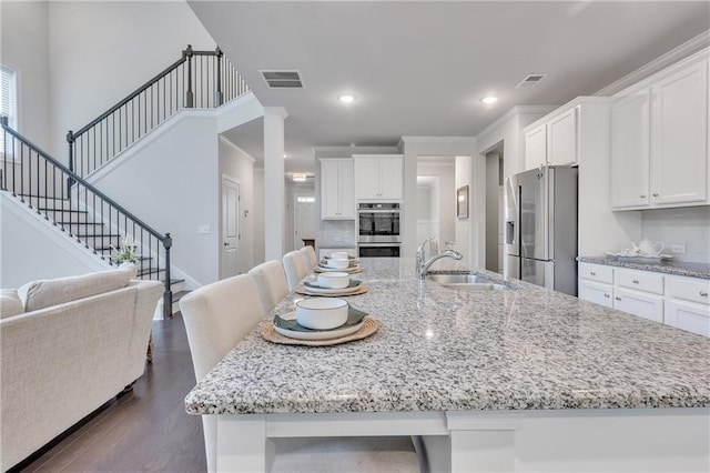 6179 Ashbranch Dr, Acworth, GA 30101 - kitchen with stainless steel appliances, a sink, white cabinets, dark wood-type flooring, and a spacious island