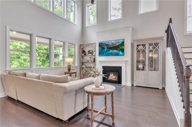 6179 Ashbranch Dr, Acworth, GA 30101 - living area with a towering ceiling, stairs, dark wood-type flooring, a glass covered fireplace, and baseboards