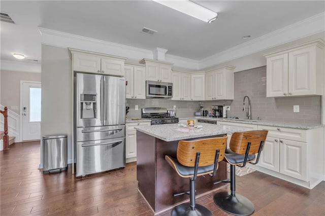 kitchen with appliances with stainless steel finishes, dark wood-style flooring, a sink, and visible vents