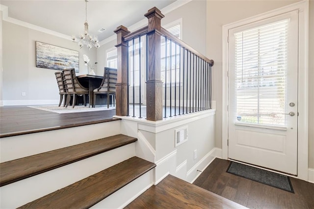 foyer entrance featuring crown molding, dark wood-type flooring, baseboards, a chandelier, and stairway