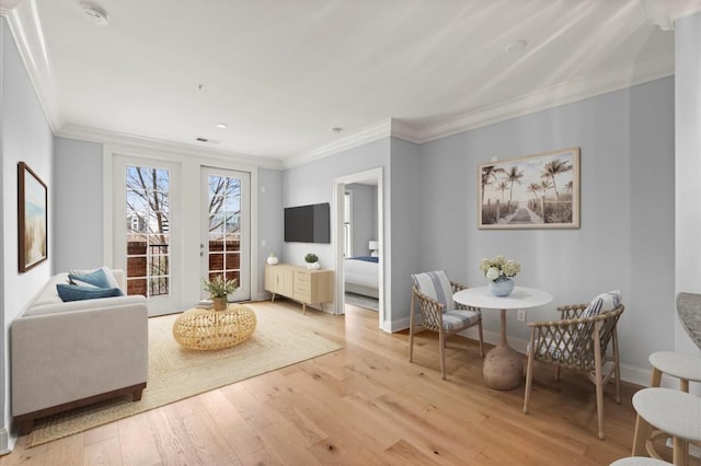 living area with light wood-style floors, visible vents, crown molding, and baseboards