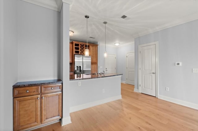 kitchen with light wood-style flooring, stainless steel refrigerator with ice dispenser, dark stone counters, decorative light fixtures, and crown molding