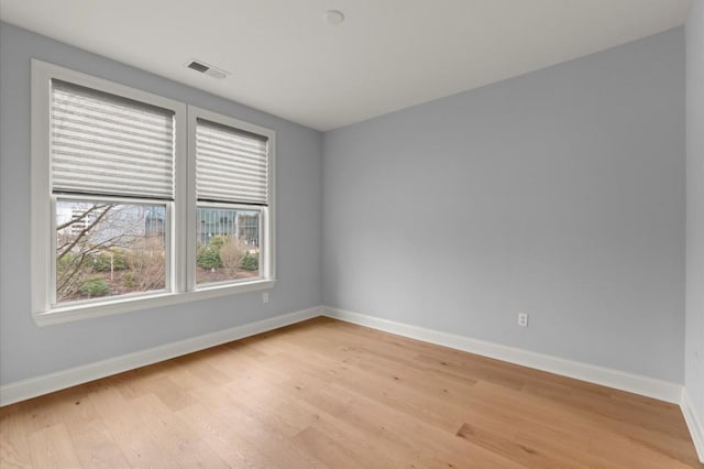 unfurnished room featuring light wood-type flooring, visible vents, and baseboards