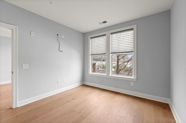 spare room featuring baseboards, visible vents, and light wood finished floors