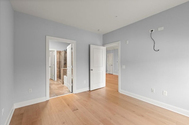 unfurnished bedroom featuring light wood finished floors, baseboards, and connected bathroom