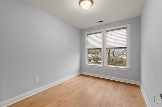 unfurnished room with light wood-type flooring, visible vents, and baseboards