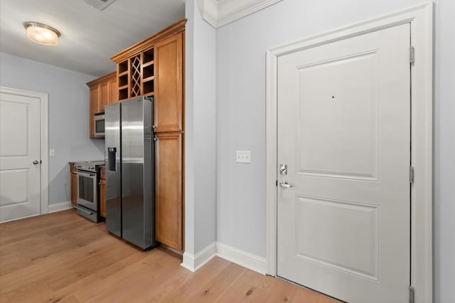 kitchen featuring stainless steel appliances, brown cabinetry, light wood-style floors, and baseboards