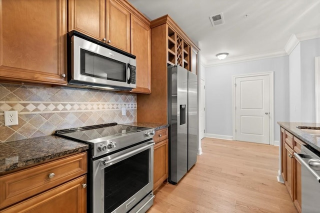 kitchen with light wood finished floors, visible vents, brown cabinetry, stainless steel appliances, and crown molding