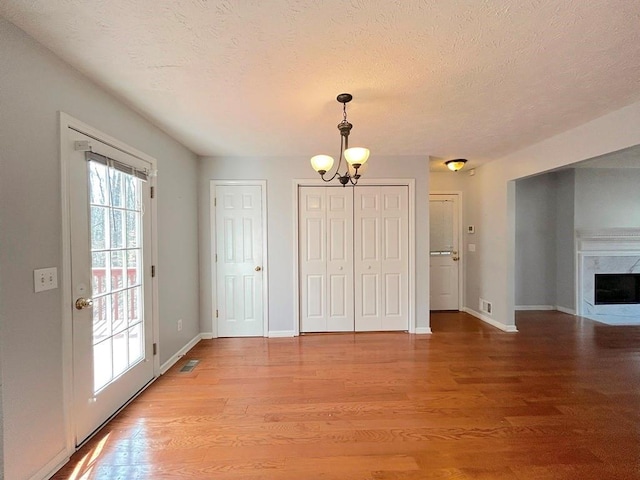 interior space with a notable chandelier, light wood-style flooring, visible vents, and baseboards