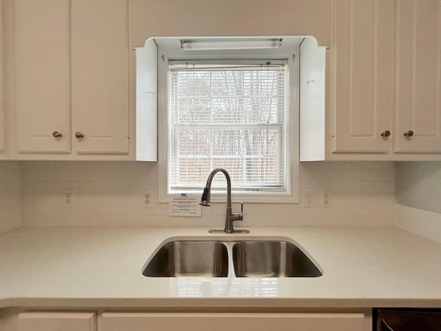 kitchen with light countertops, white cabinets, and a sink