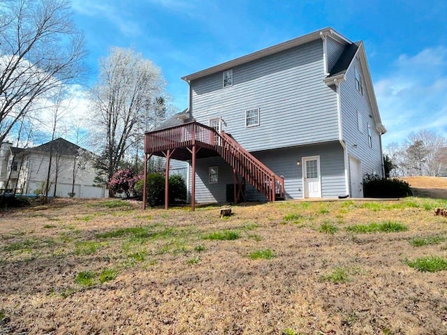 back of house with stairway, an attached garage, and a wooden deck