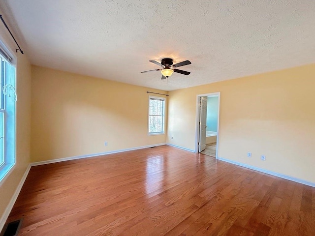 unfurnished room featuring visible vents, a textured ceiling, ceiling fan, and light wood finished floors