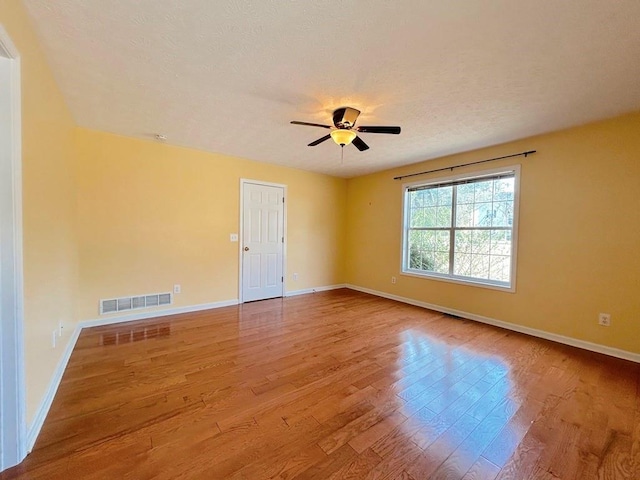 unfurnished room featuring visible vents, baseboards, ceiling fan, and wood finished floors