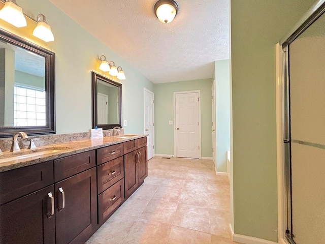 full bath with an enclosed shower, a textured ceiling, and a sink