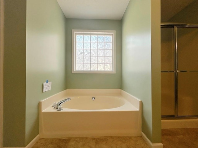 bathroom featuring tile patterned flooring, a shower stall, a bath, and baseboards