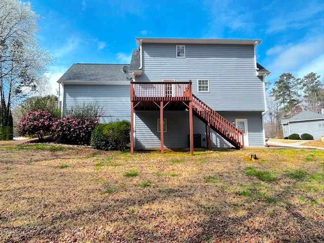 back of property with a wooden deck, a yard, and stairs