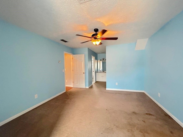 unfurnished bedroom featuring visible vents, baseboards, carpet floors, a textured ceiling, and ensuite bath