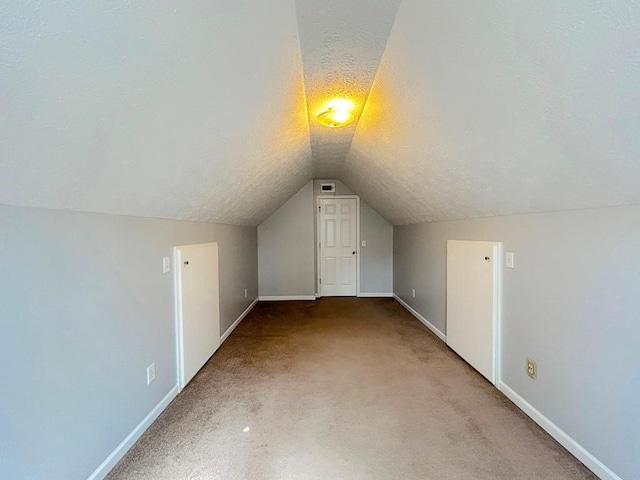 bonus room featuring baseboards, a textured ceiling, vaulted ceiling, and carpet