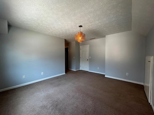 spare room featuring visible vents, baseboards, dark carpet, lofted ceiling, and a textured ceiling