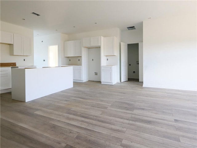 kitchen featuring white cabinets, a center island, and light hardwood / wood-style flooring