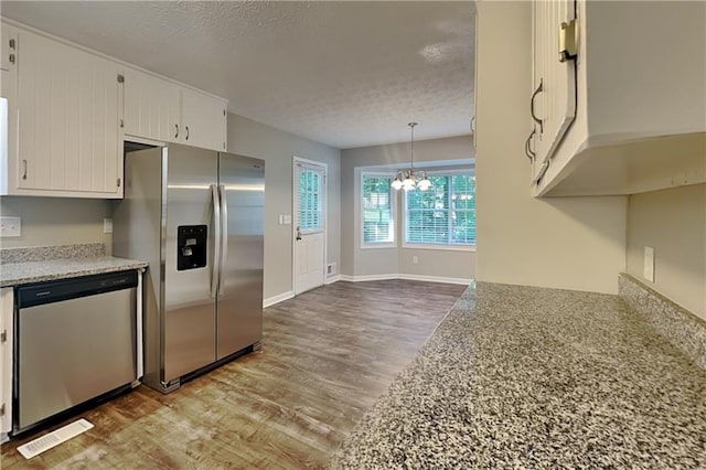 1011 Darvin Ln NW, Kennesaw, GA 30144 - kitchen featuring appliances with stainless steel finishes, a textured ceiling, wood finished floors, a chandelier, and white cabinetry