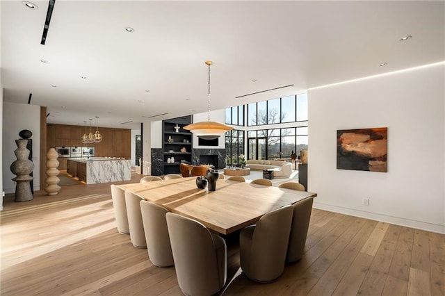 dining area with a notable chandelier, light hardwood / wood-style floors, and floor to ceiling windows