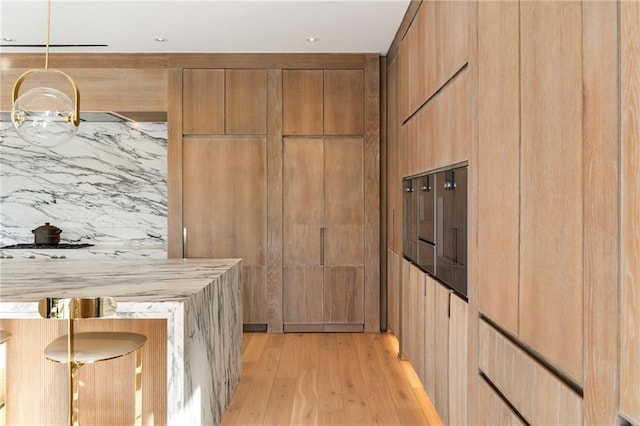 kitchen featuring hanging light fixtures, light hardwood / wood-style floors, and wood walls