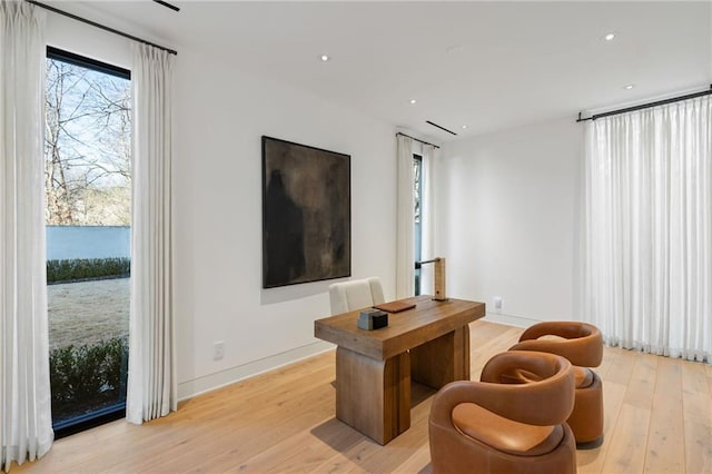 living room featuring light hardwood / wood-style flooring, a wealth of natural light, and a water view