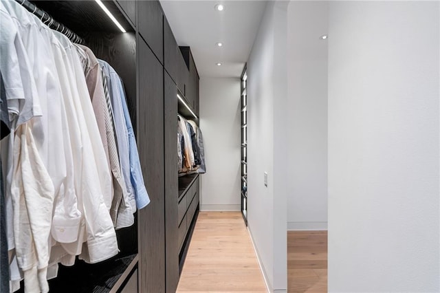 walk in closet with light hardwood / wood-style flooring