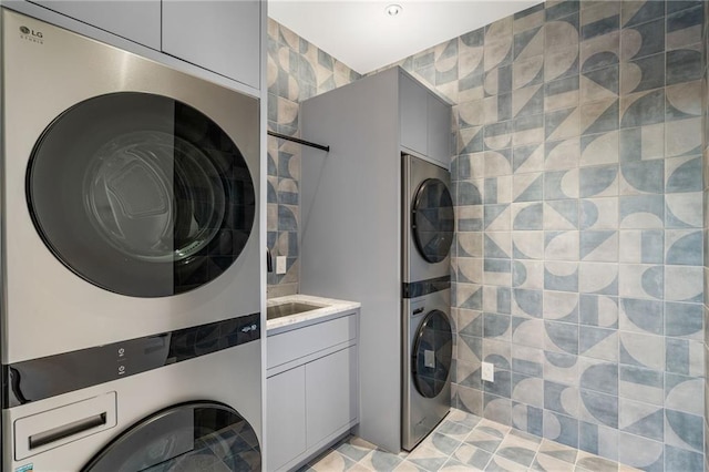 clothes washing area featuring cabinets and stacked washer / drying machine