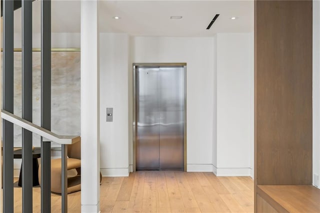 corridor with elevator and light wood-type flooring