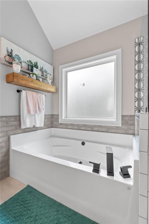 full bath featuring a garden tub, lofted ceiling, carpet floors, and tile walls