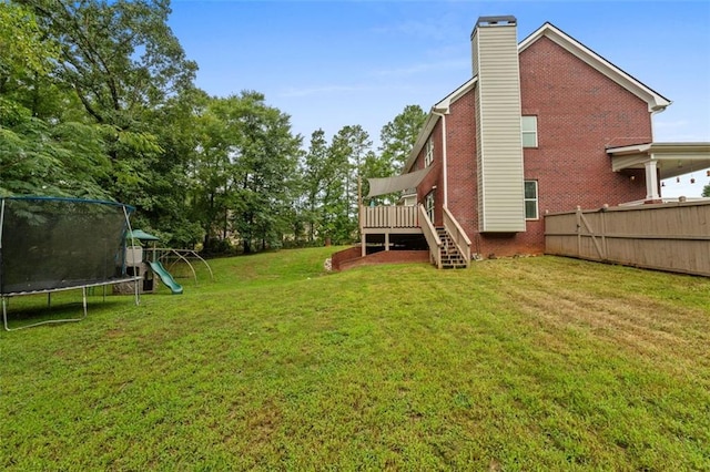view of yard with stairway, a playground, fence, a trampoline, and a deck