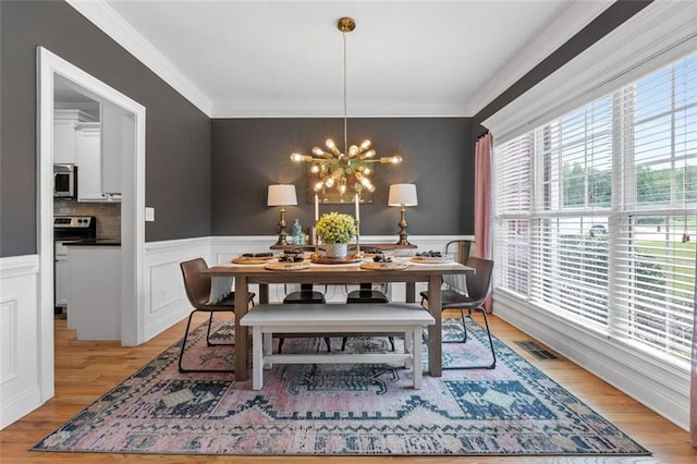 dining space with light wood-style flooring, visible vents, crown molding, and an inviting chandelier