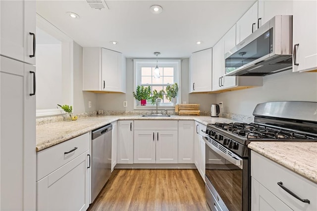 1995 Raleigh Tavern Dr, Roswell, GA 30076 - kitchen featuring stainless steel appliances, a sink, white cabinetry, light wood finished floors, and recessed lighting