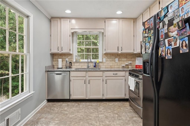 kitchen featuring sink, tasteful backsplash, light stone counters, and stainless steel appliances