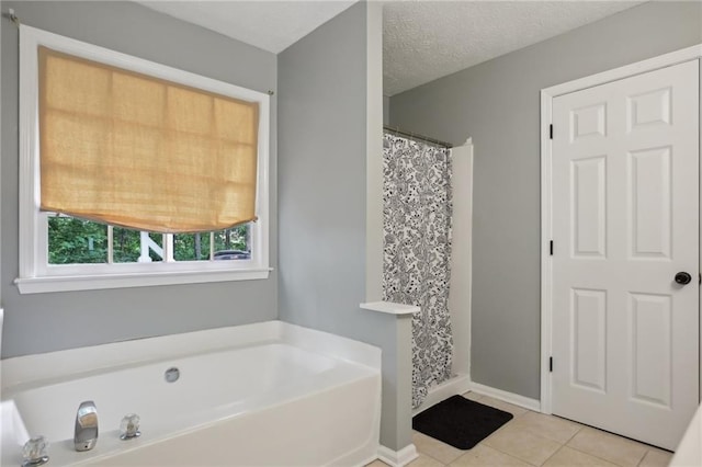 bathroom with tile floors, a washtub, and a textured ceiling