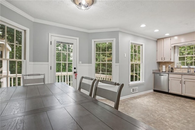 unfurnished dining area featuring a healthy amount of sunlight, a textured ceiling, ornamental molding, and light tile floors