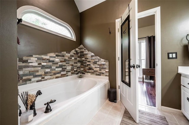 bathroom with a healthy amount of sunlight, tile patterned flooring, lofted ceiling, and vanity