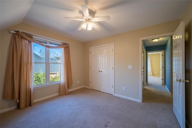 unfurnished bedroom featuring ceiling fan, vaulted ceiling, light carpet, and a closet