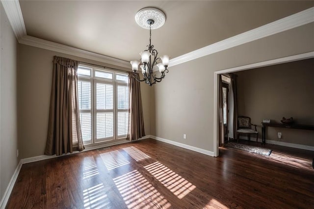 spare room featuring dark hardwood / wood-style flooring, crown molding, and a chandelier