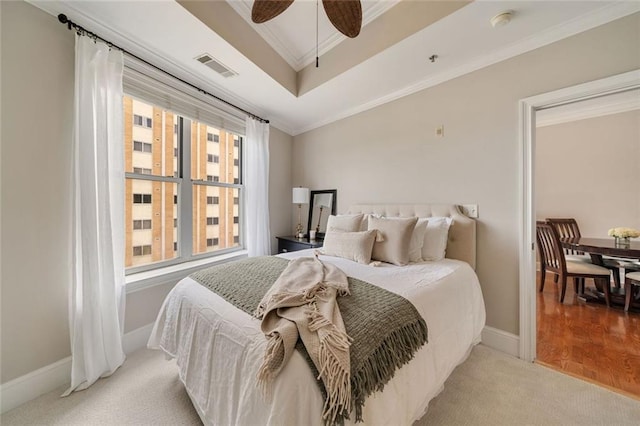 bedroom with crown molding, light carpet, baseboards, a tray ceiling, and a ceiling fan