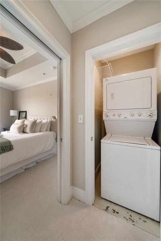 laundry area with estacked washer and dryer, crown molding, carpet floors, and baseboards