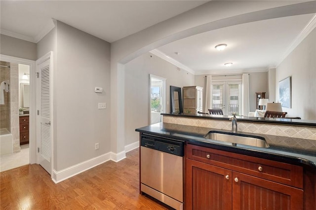 kitchen with dishwasher, a sink, arched walkways, dark countertops, and ornamental molding